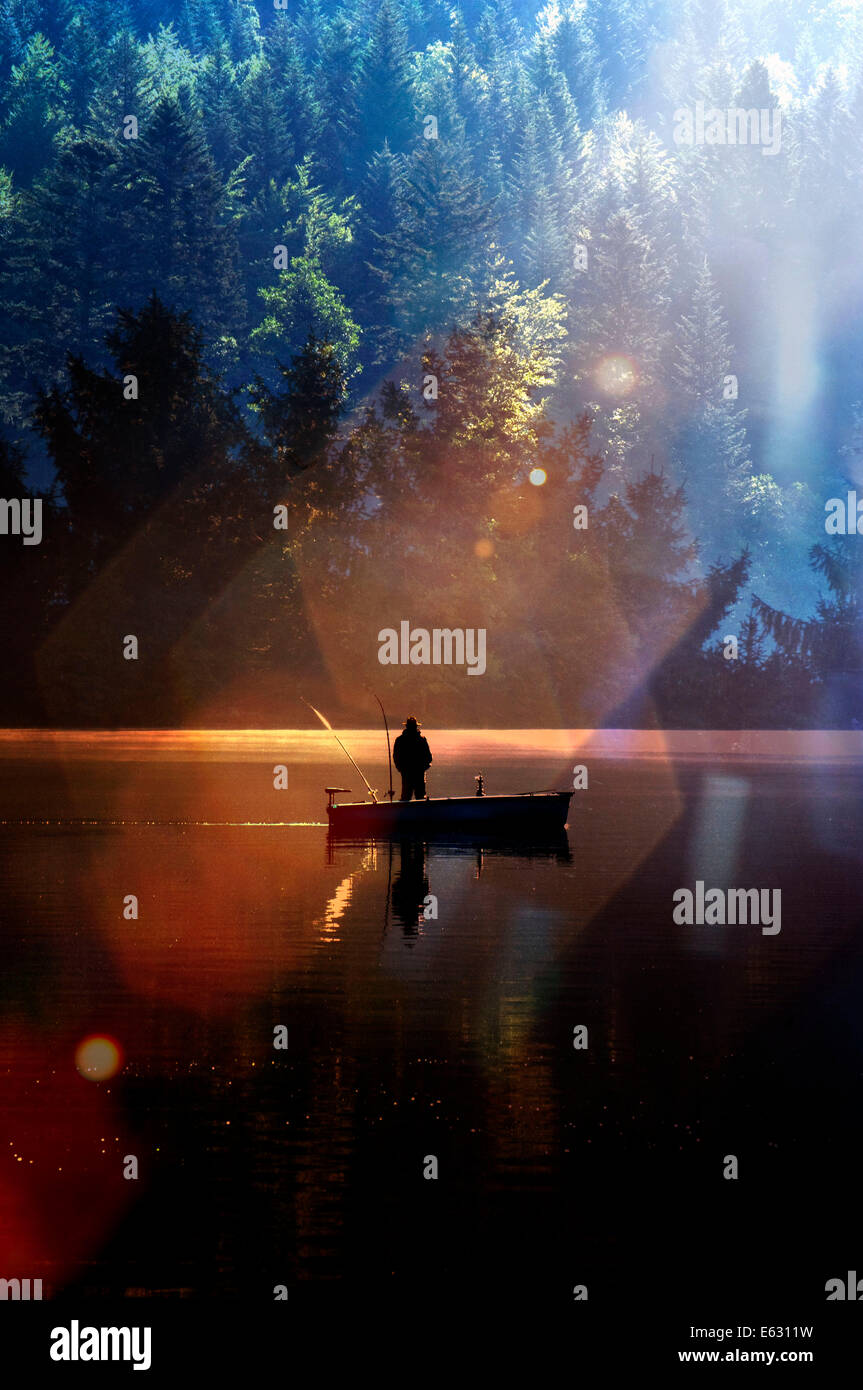 Ein Fischer an einem See mit Sunburst Lichtwirkung. Stockfoto