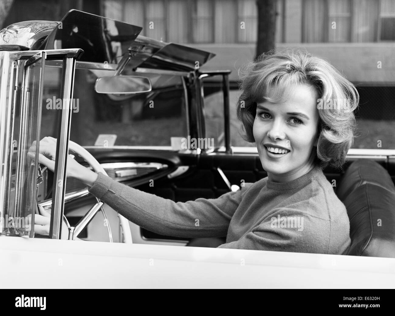 1960ER JAHREN LÄCHELND BLONDE AUTOFAHRERIN CABRIO BLICK IN DIE KAMERA Stockfoto