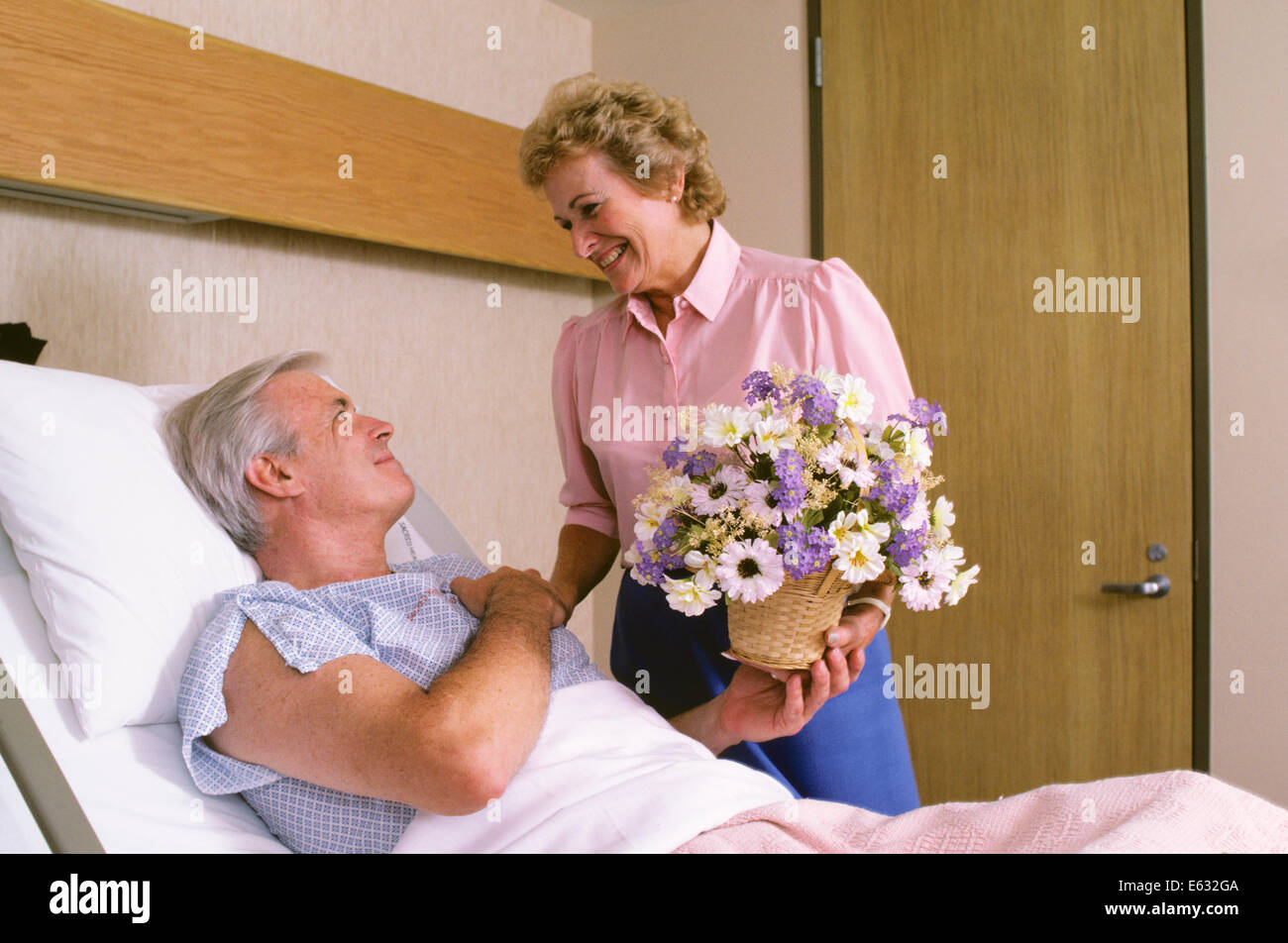 1980ER JAHRE FRAU GEBEN BLUMEN IM KRANKENHAUS MANN IM BETT LIEGEND Stockfotografie Alamy