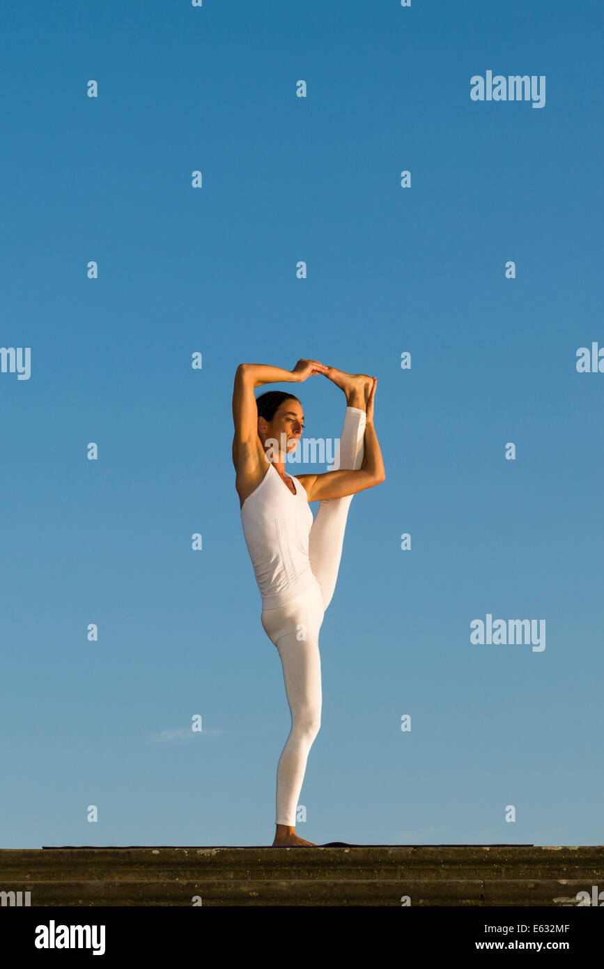 Junge Frau praktizieren Hatha Yoga im Freien, zeigen die Pose Utthita Hasta Pandangusthasana, hob die Hand zur Großzehe-pose Stockfoto