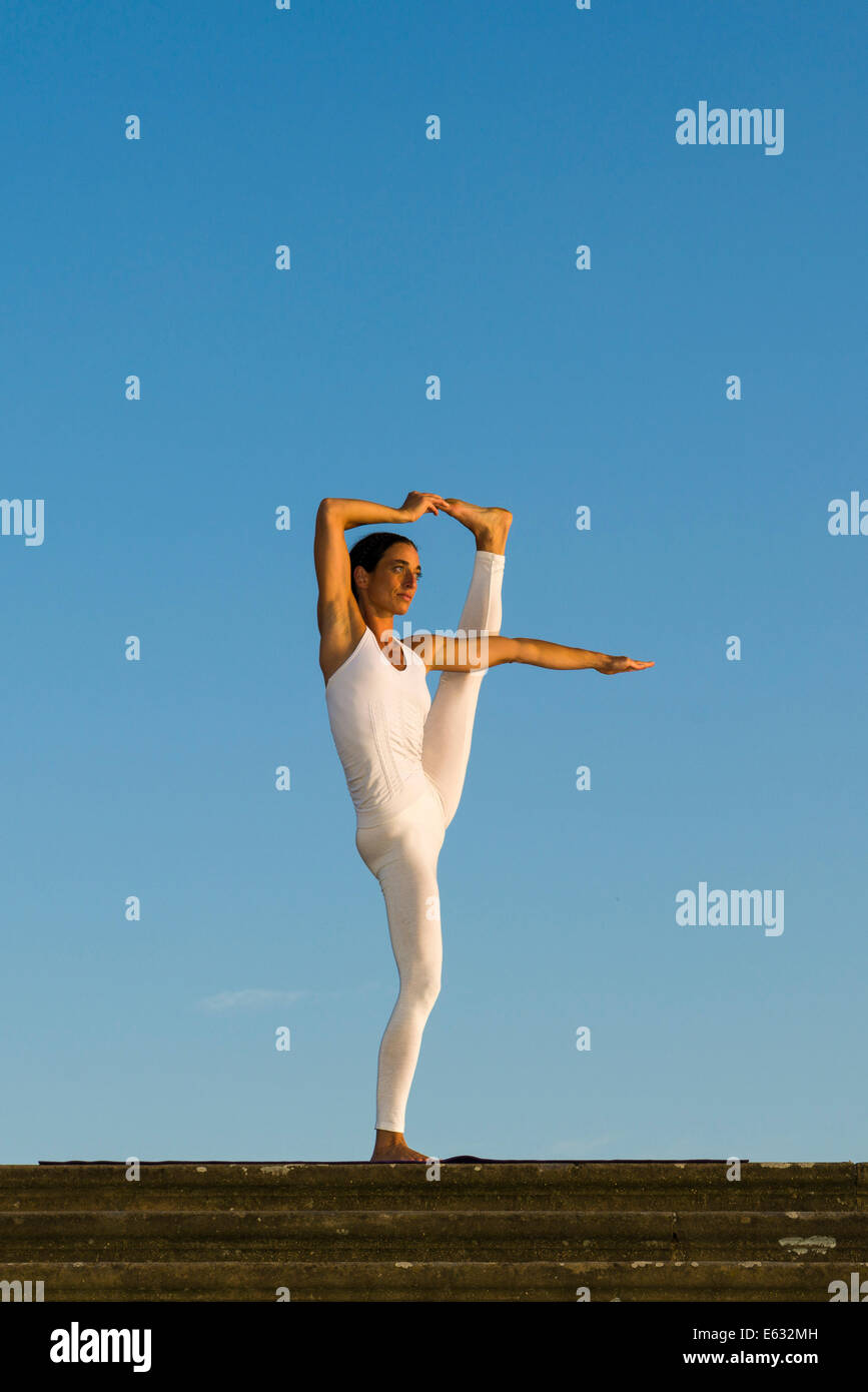 Junge Frau praktizieren Hatha Yoga im Freien, zeigen die Pose Utthita Hasta Pandangusthasana, hob die Hand zur Großzehe-pose Stockfoto