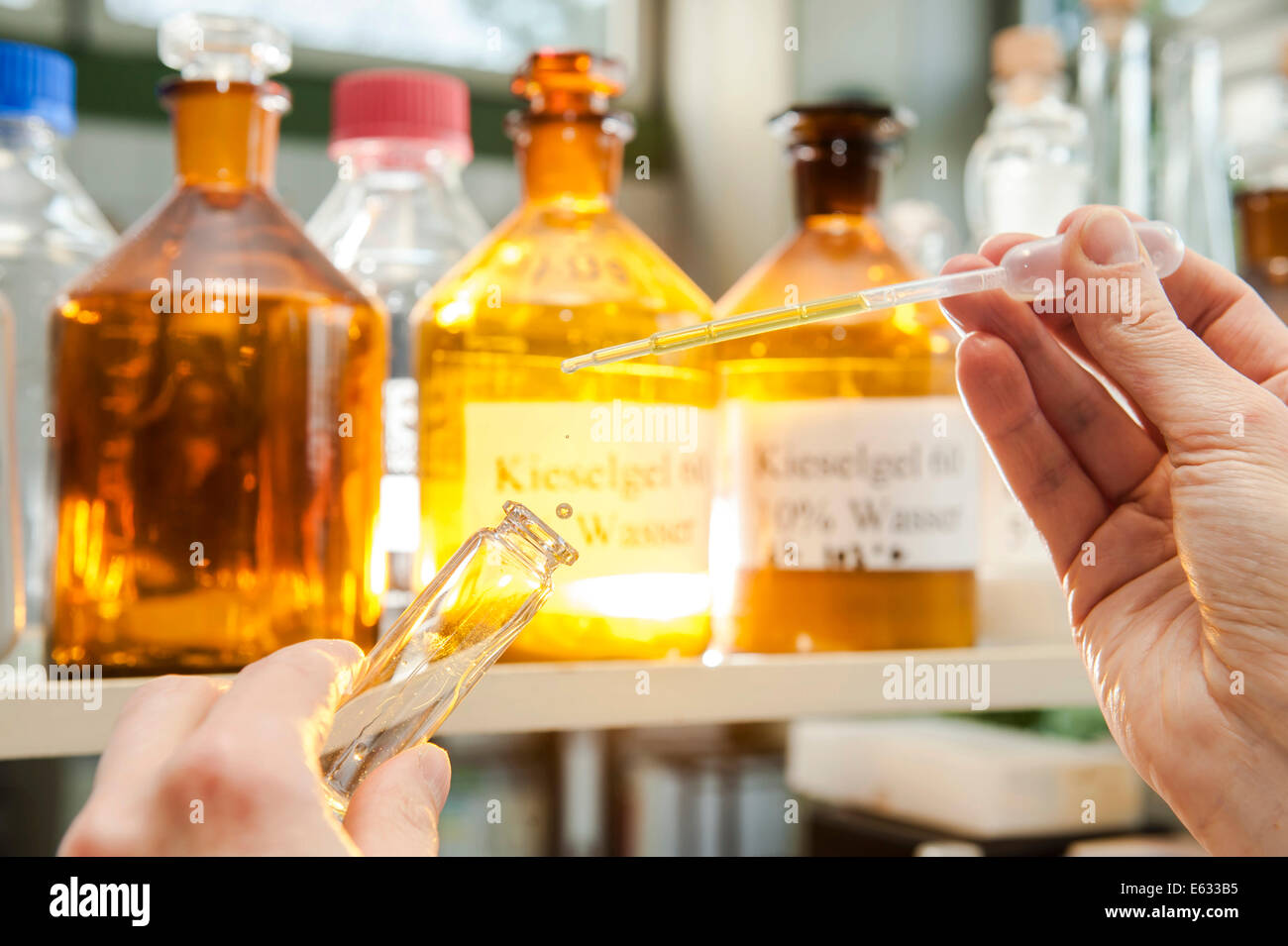 Ein Labor-Arbeiter mit einer Pipette auf eine chemische Flüssigkeit in einen Glasbehälter füllen Stockfoto