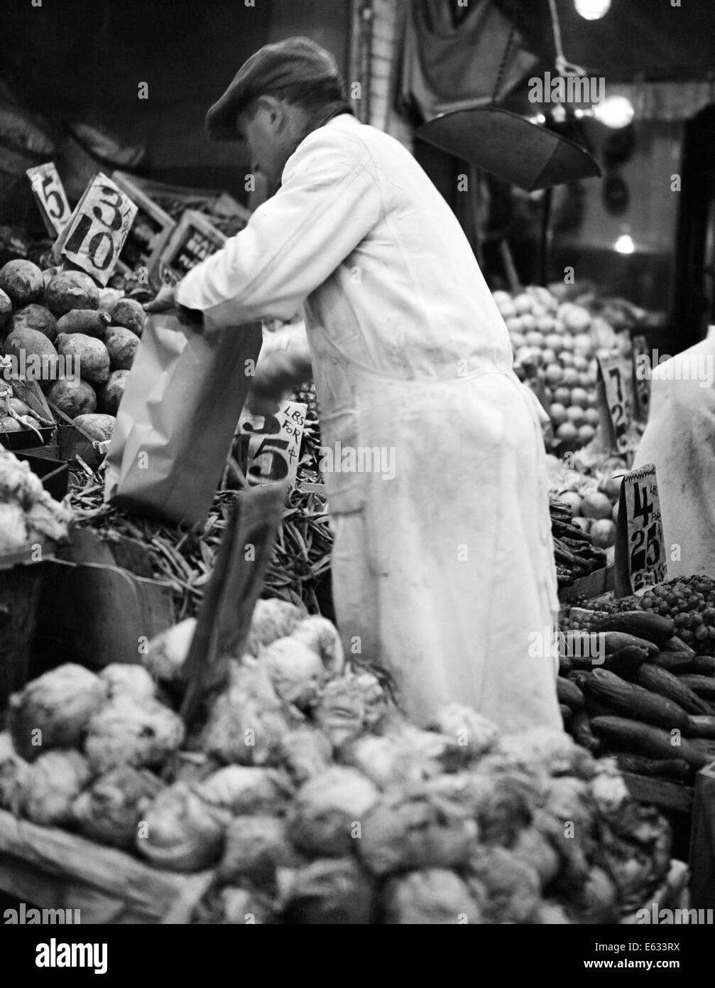 1930ER JAHRE MANN LEBENSMITTELHÄNDLER OBST UND GEMÜSE PRODUZIEREN MARKT IN NEW YORK CITY USA Stockfoto