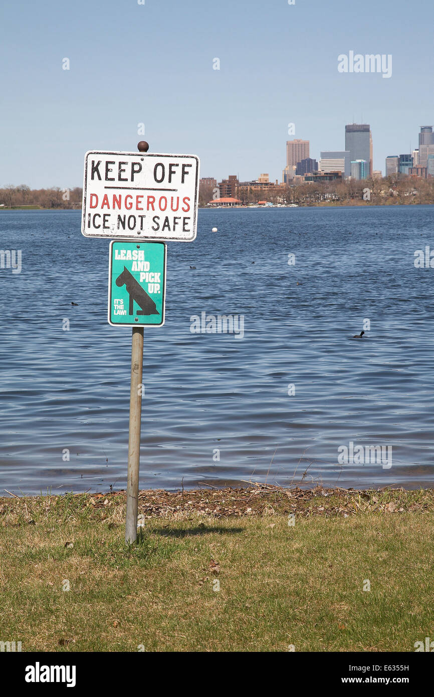 Ein Warnschild am Ufer des Lake Calhoun mit der Stadt von Minneapolis in der Ferne. Stockfoto