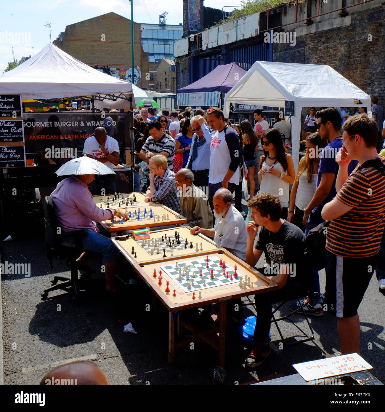 Mann spielt Schach gegen 4 andere, die alle zur gleichen Zeit in der Brick Lane, Shoreditch, London, England Stockfoto