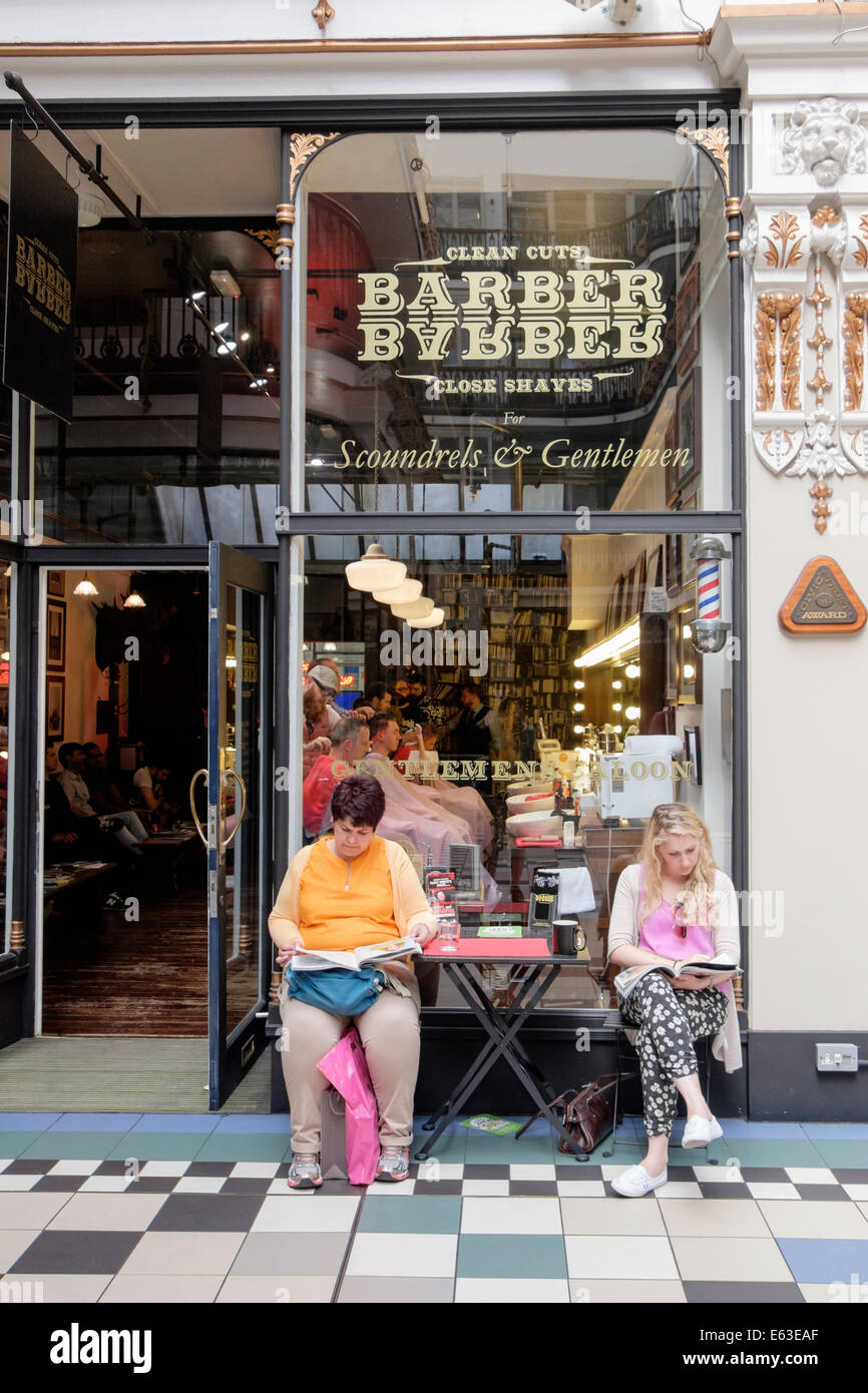 Zwei Frauen sitzen warten außerhalb BarberBarber Herren nur Barbershop in Barton Arcade, Manchester, England, UK, Großbritannien Stockfoto