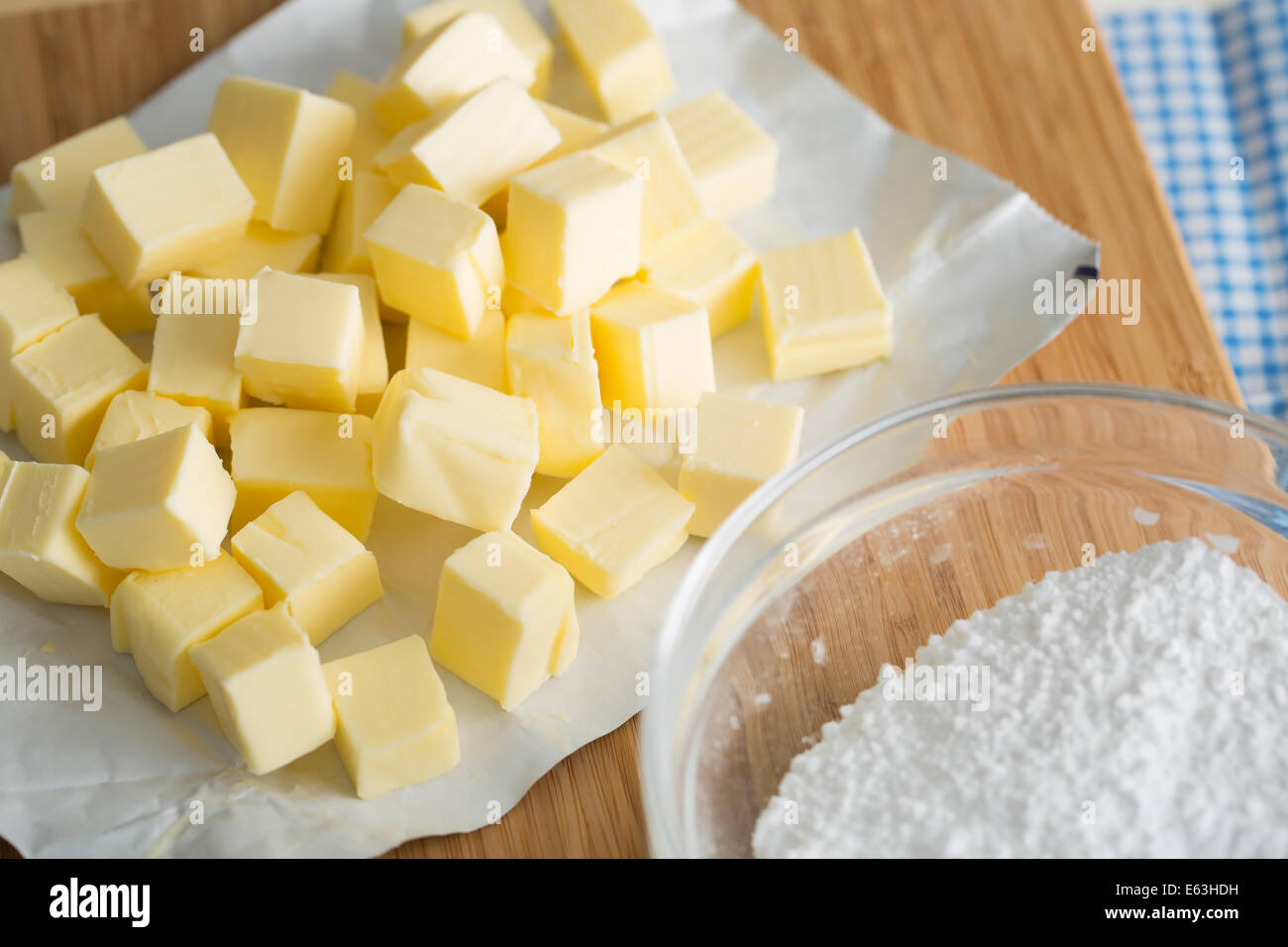 Frische Butter Würfel auf Schneidebrett mit Schüssel mit Mehl. Stockfoto