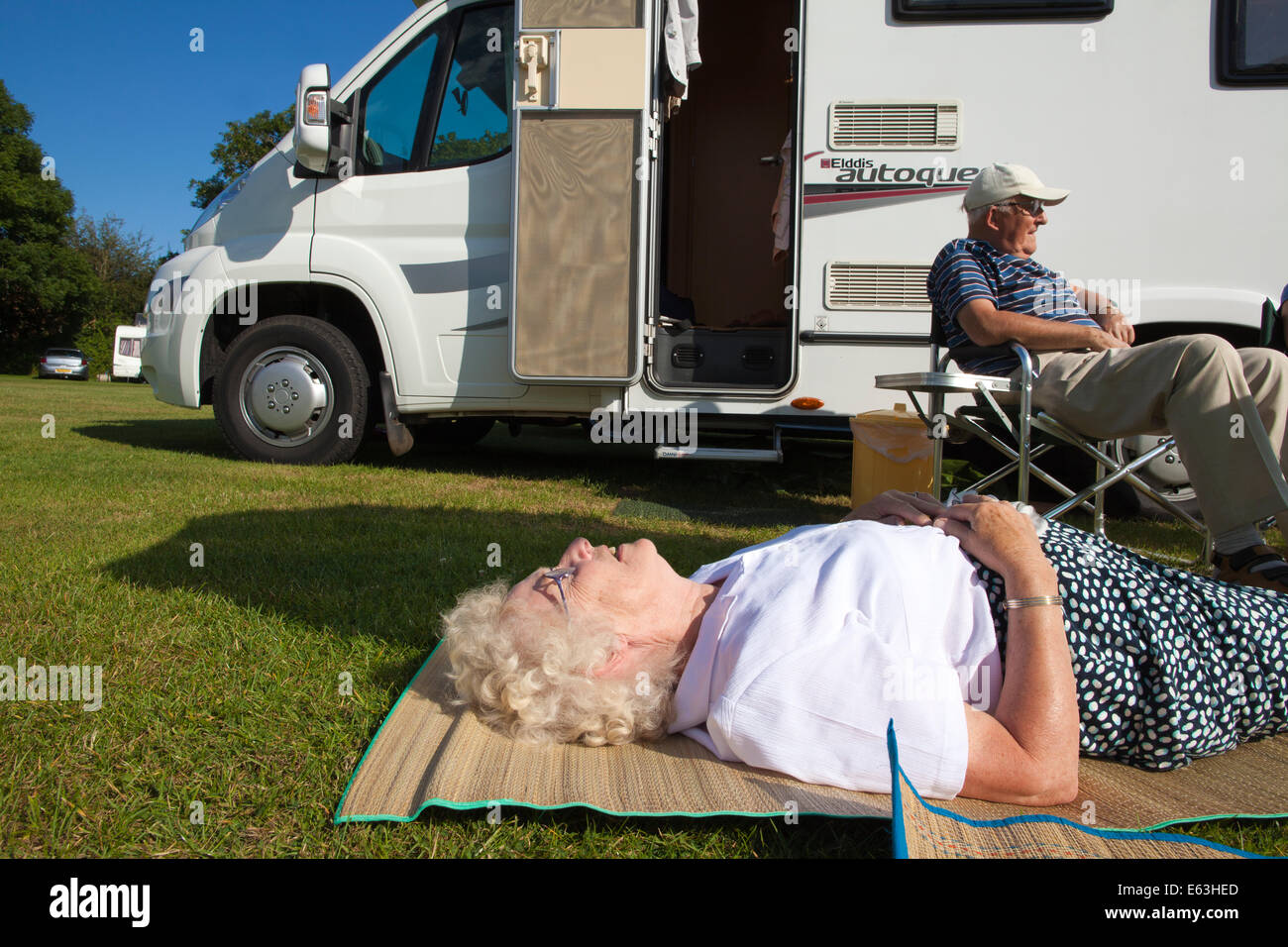 Ältere Frau und Mann zum Entspannen in der Sonne außerhalb ihrer Wohnwagen genießen Ruhestand in Devon, England, UK Stockfoto