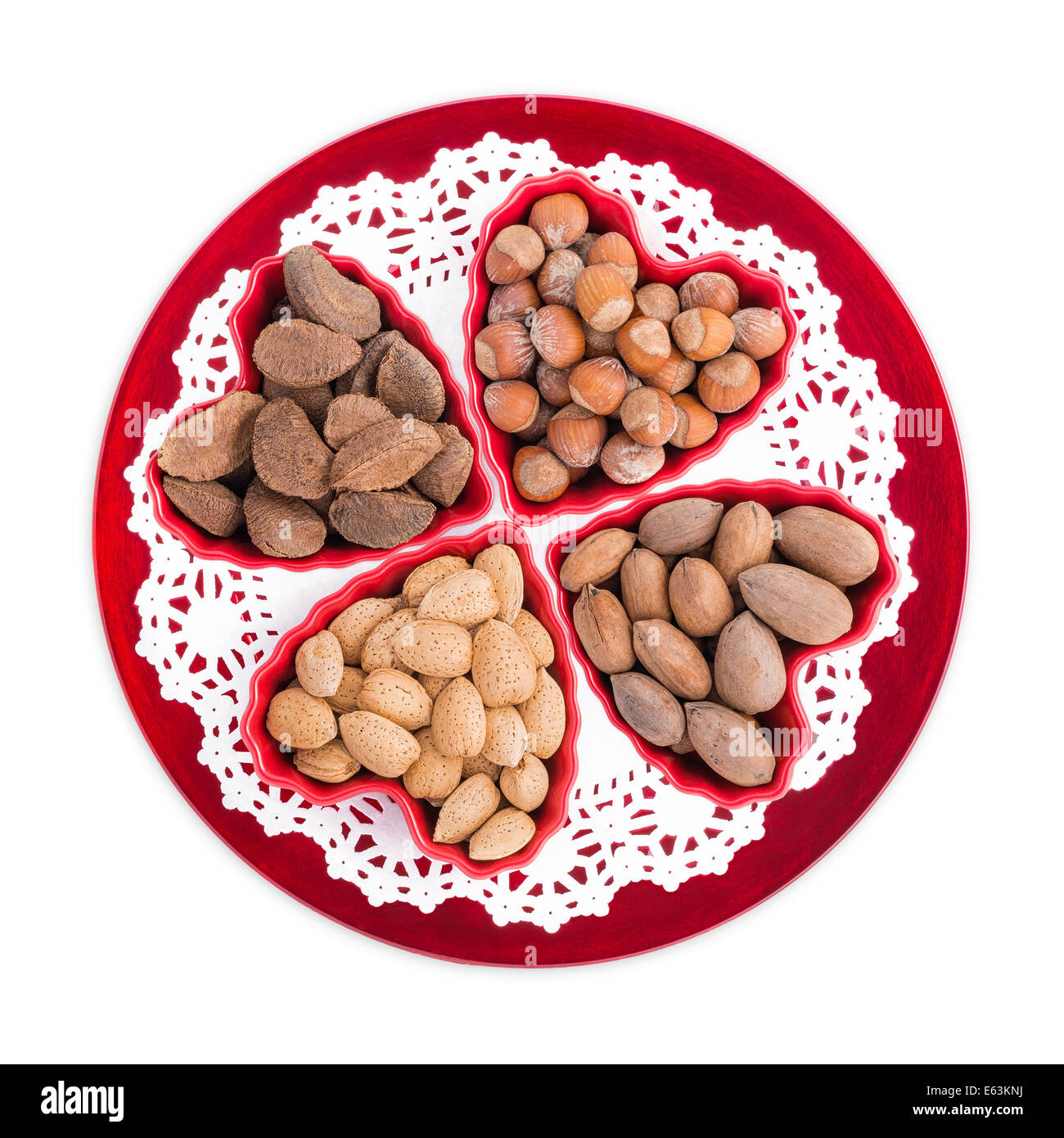 Gruppe Herz-gesunde Nüsse wie Mandeln, Haselnüsse, Pekannüsse und Paranüsse in Herz-Form-Schalen auf einer roten Platte angezeigt Stockfoto