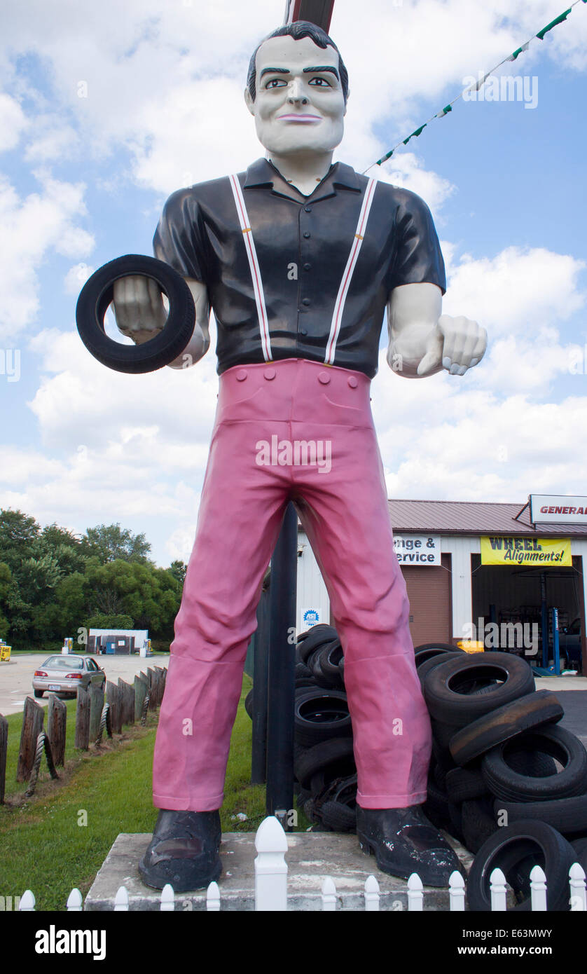 Eine klassische Muffler man-Statue in knallig rosa Hosen steht vor einer Garage in Magnolia, New Jersey. Stockfoto