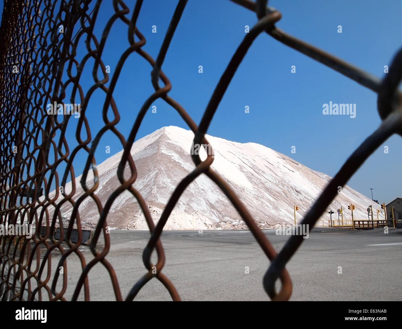 Ein Berg von Streusalz sitzt sicher hinter einem Maschendrahtzaun gesperrt. Stockfoto