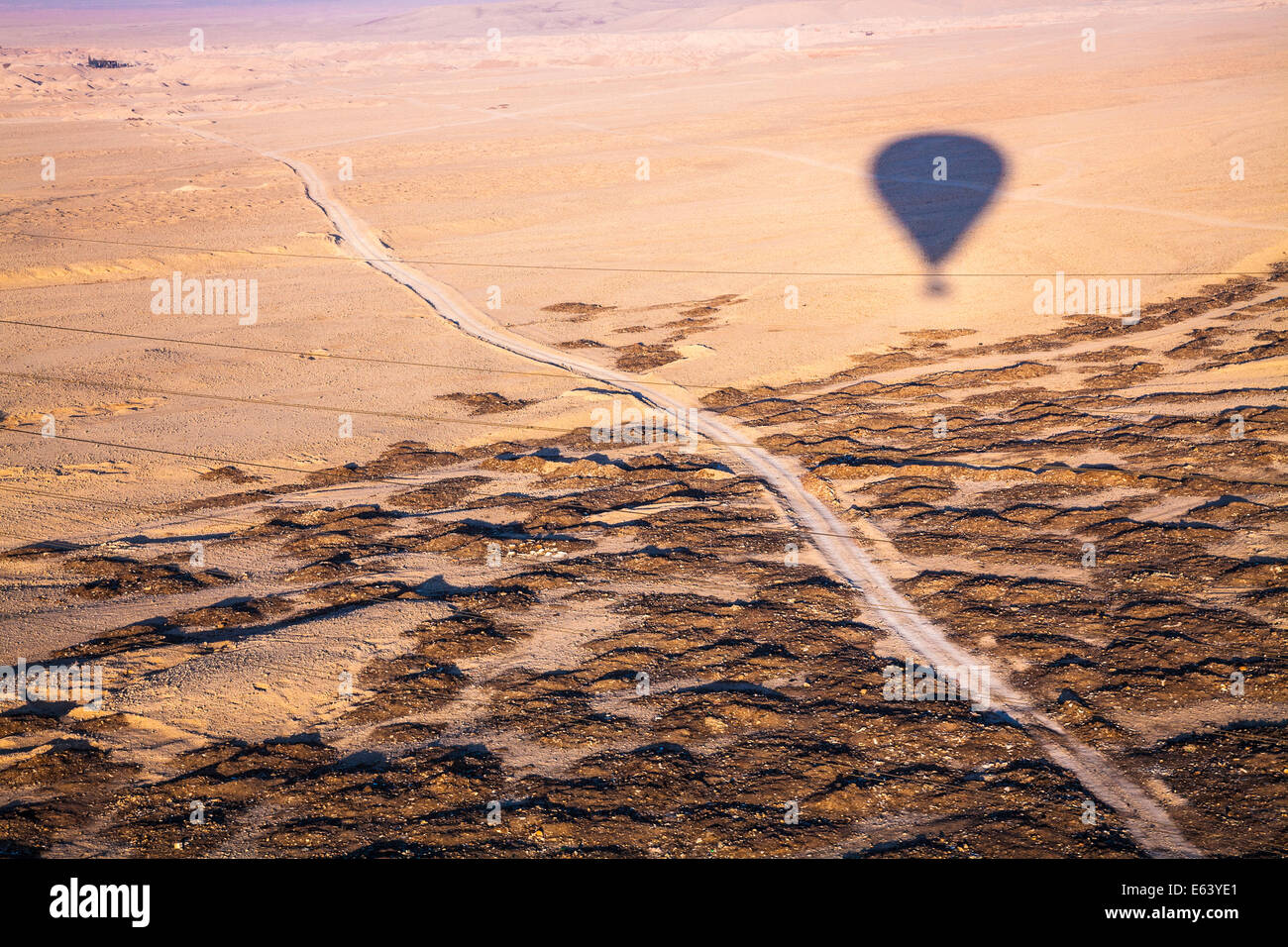 Der Schatten von einem Heißluftballon bei Sonnenaufgang über der Wüste von der West Bank des Nils in Ägypten fliegen. Stockfoto