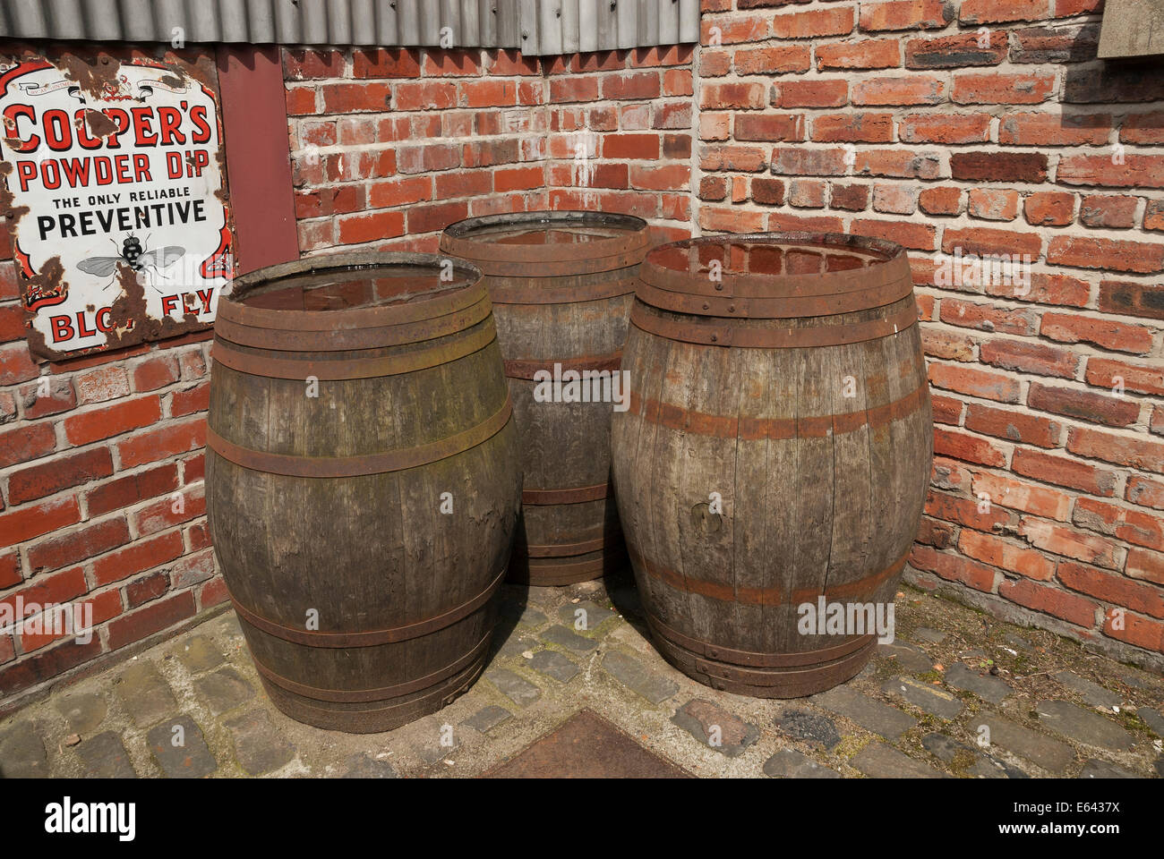 Drei hölzerne Bierfaß in Hof gegen Mauer gespeichert. Stockfoto