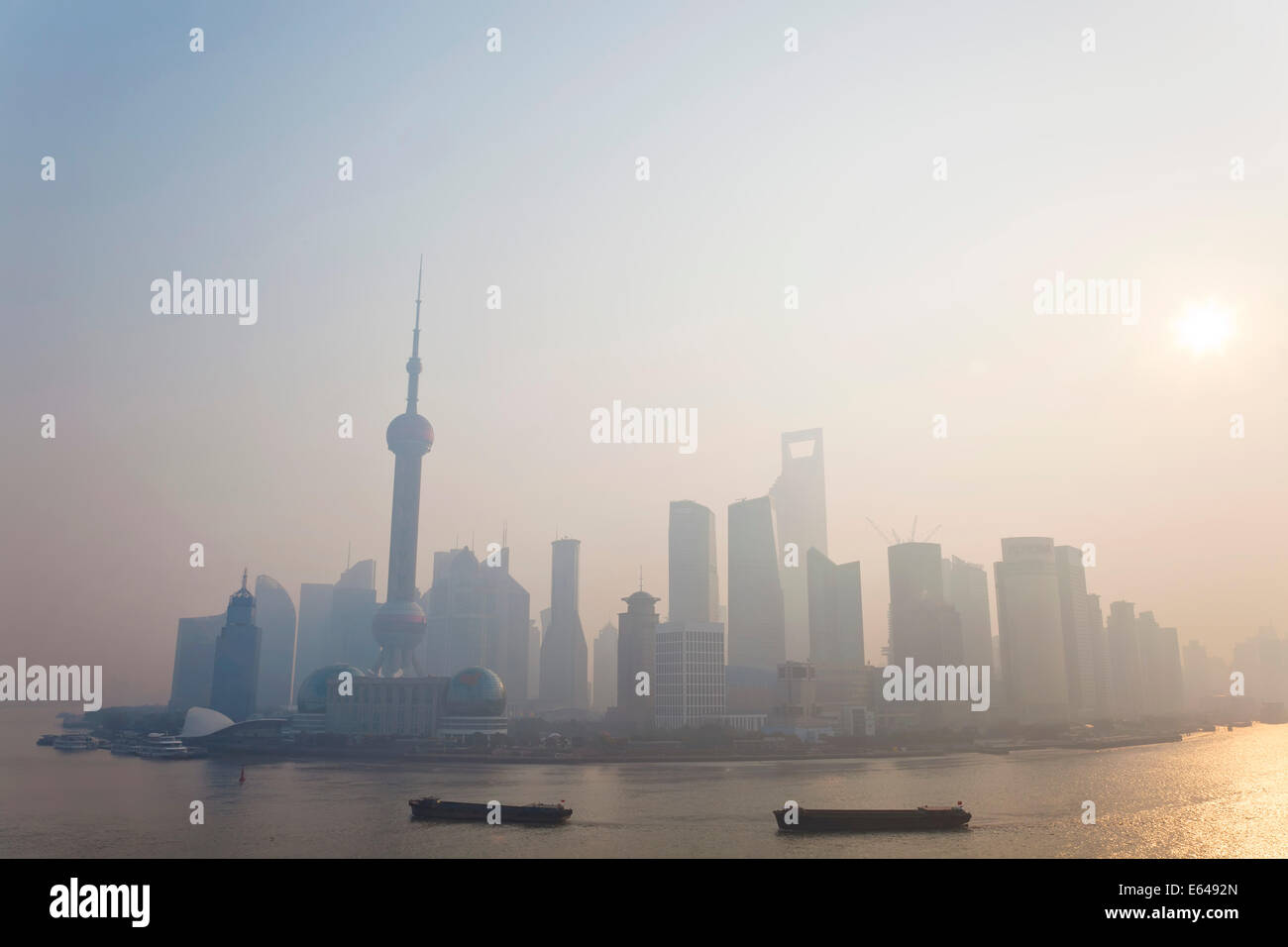 Sonnenaufgang über der Skyline von Pudong & Lastkähne am Huangpu-Fluss, Shanghai, China Stockfoto