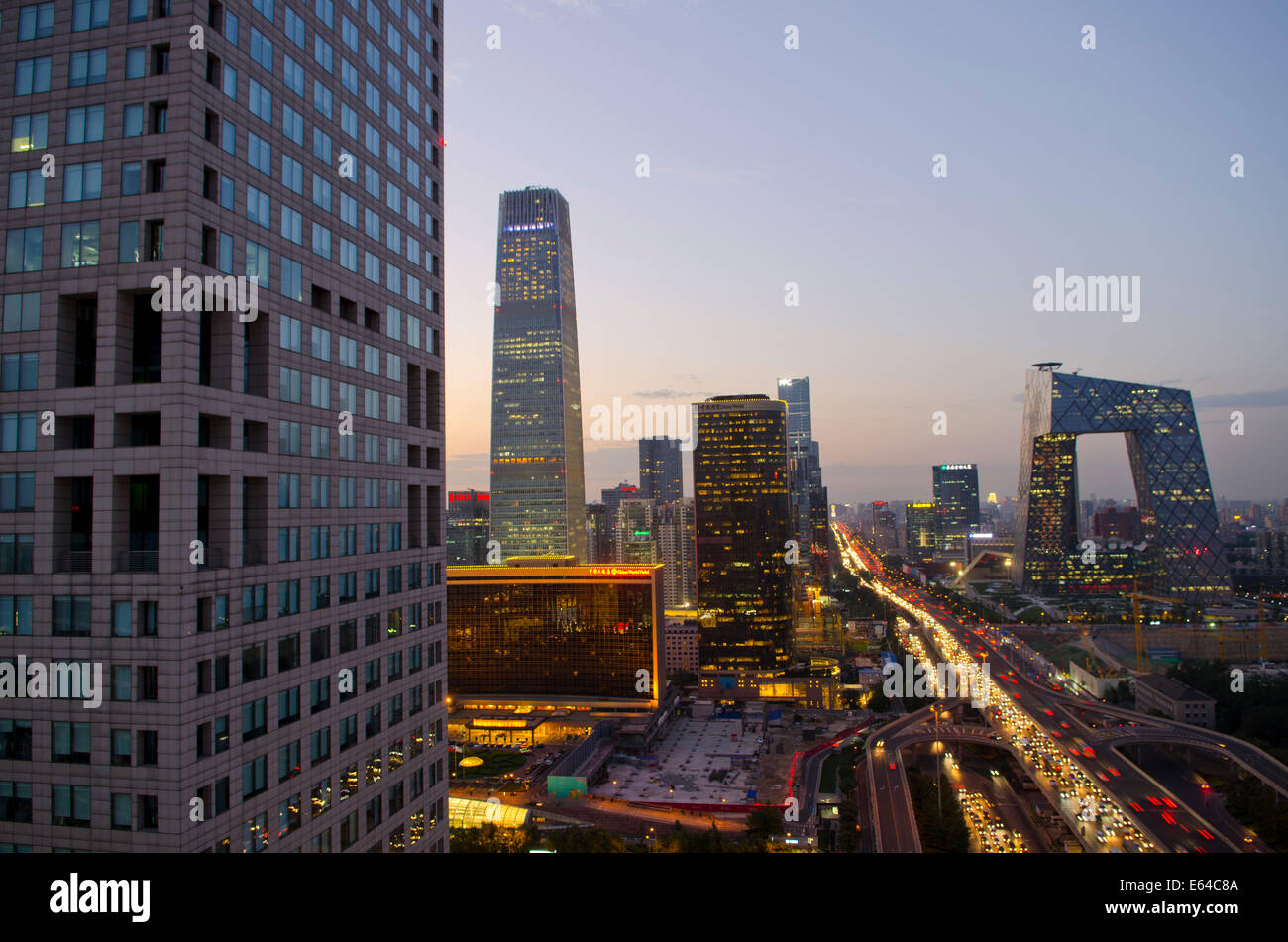 Schöner Blick auf die Skyline der chinesischen Hauptstadt und das berühmte Wahrzeichen des CCTV-Hauptquartiers, mit den Lichtern des Verkehrs auf der dritten Ringstraße und Büros und Gebäuden, die die Szene am frühen Abend erhellen. Seltene Panoramaszene während der blauen Stunde kurz nach Sonnenuntergang mit klarem Himmel in Guomao, dem Central Business District in Peking, im Chaoyang District, China, PRC. © Olli Geibel Stockfoto