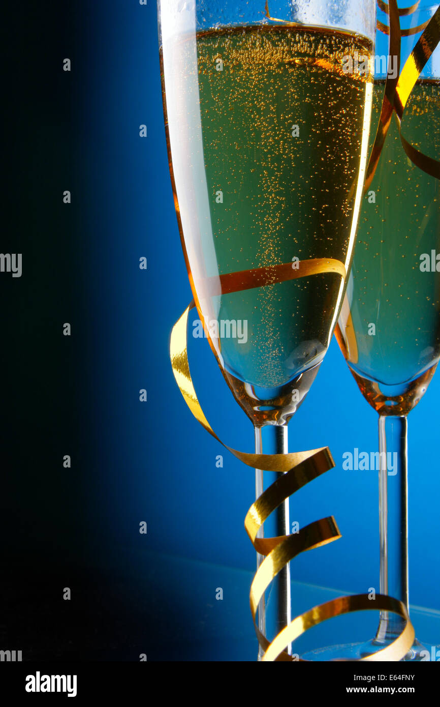 Paar Gläser Champagner mit gold Streamer auf blauem Hintergrund Stockfoto