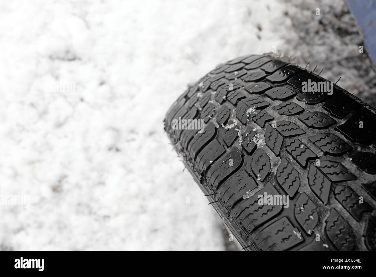 Nahaufnahme von Winterreifen auf einer verschneiten Straße Stockfoto