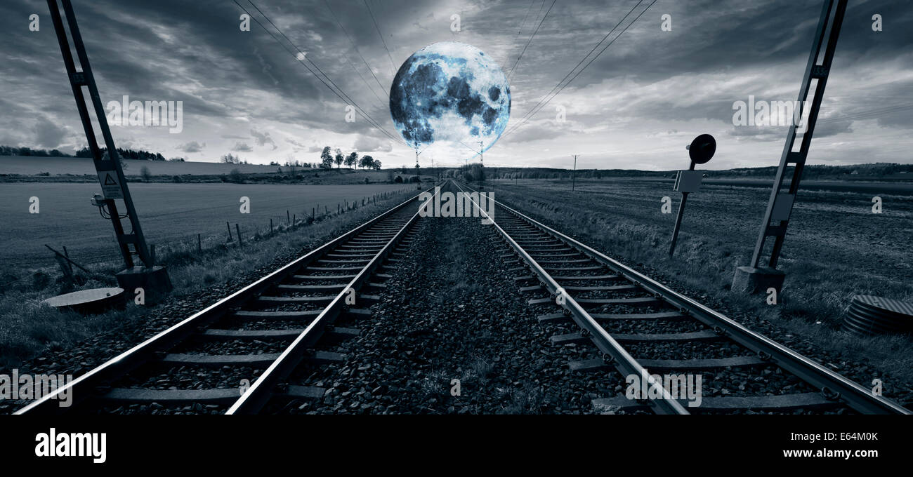 einsame Bahnstrecke mit einem riesigen surrealen Mondaufgang am Horizont Stockfoto