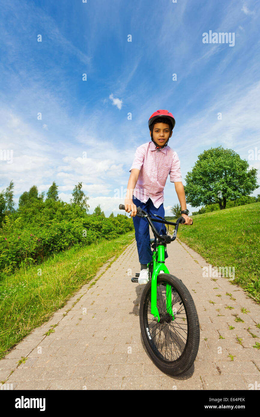 Afrikanischen jungen im roten Helm Fahrradtouren hell grün Stockfoto