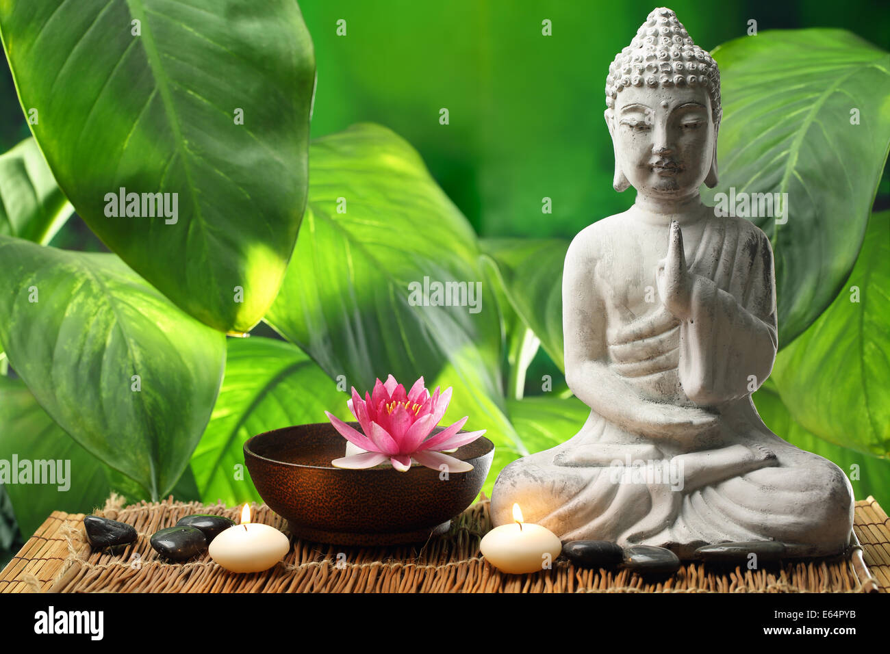 Buddha in Meditation mit Lotusblüte und brennenden Kerzen Stockfoto