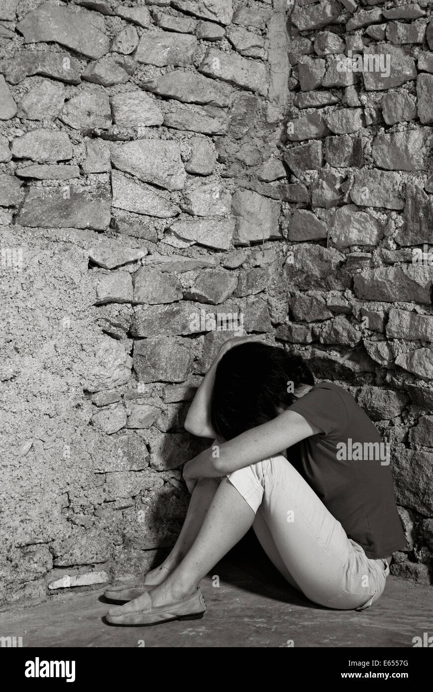 Depressive Frau mittleren Alters sitzen mit Kopf in Händen in einer Raumecke Stockfoto