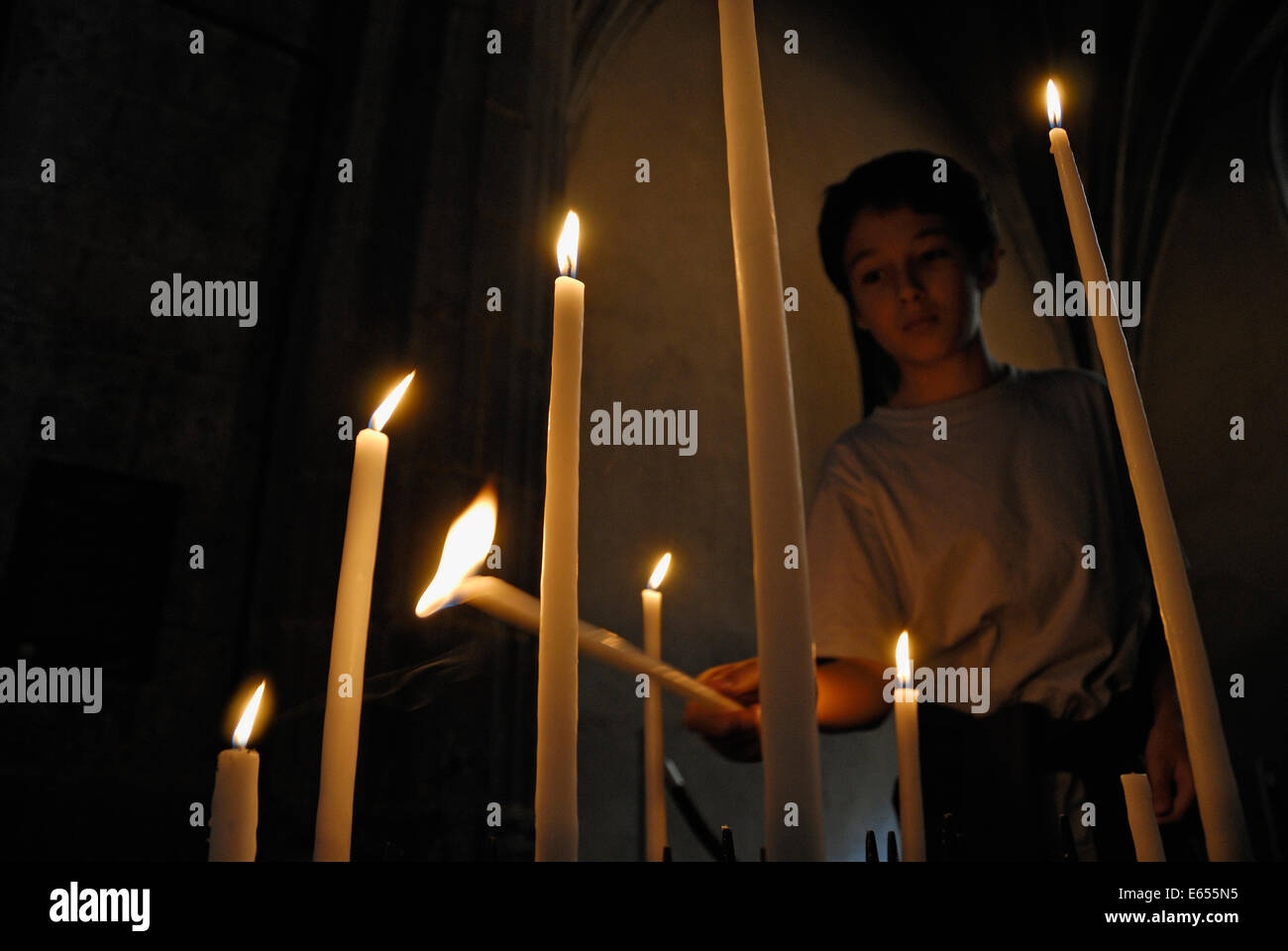 Kleiner Junge in einer Kirche eine Kerze anzünden Stockfoto