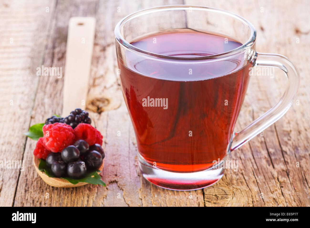 Rote Früchtetee mit Waldbeeren in Holzlöffel auf braunen Holztisch Stockfoto