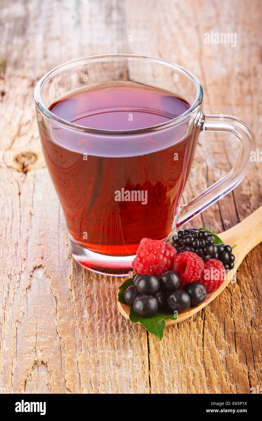 Rote Früchtetee mit Waldbeeren in Holzlöffel auf braunen Holztisch Stockfoto