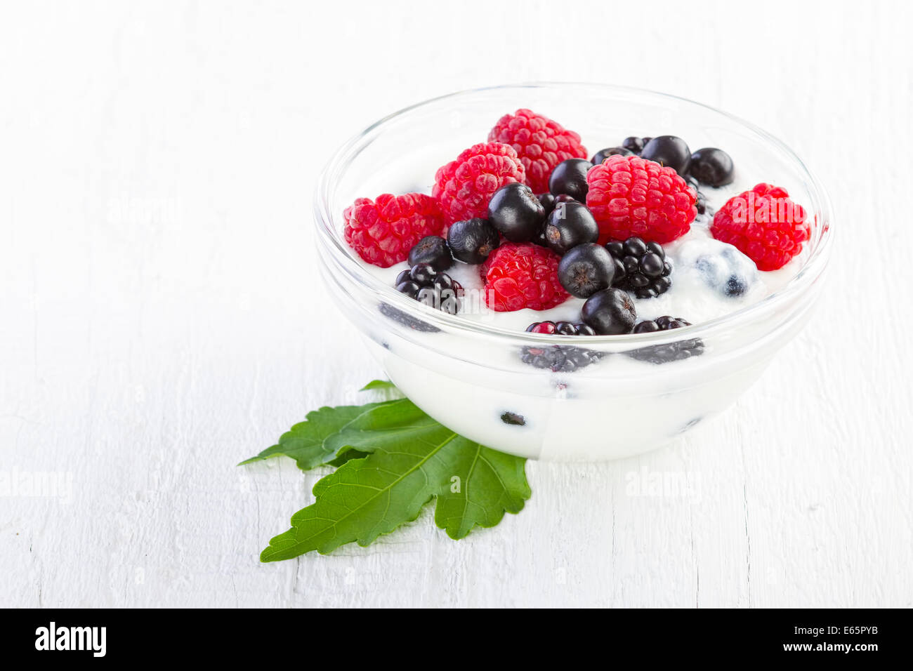 Joghurt mit Waldbeeren in hölzerne Schüssel weißen Hintergrund ...