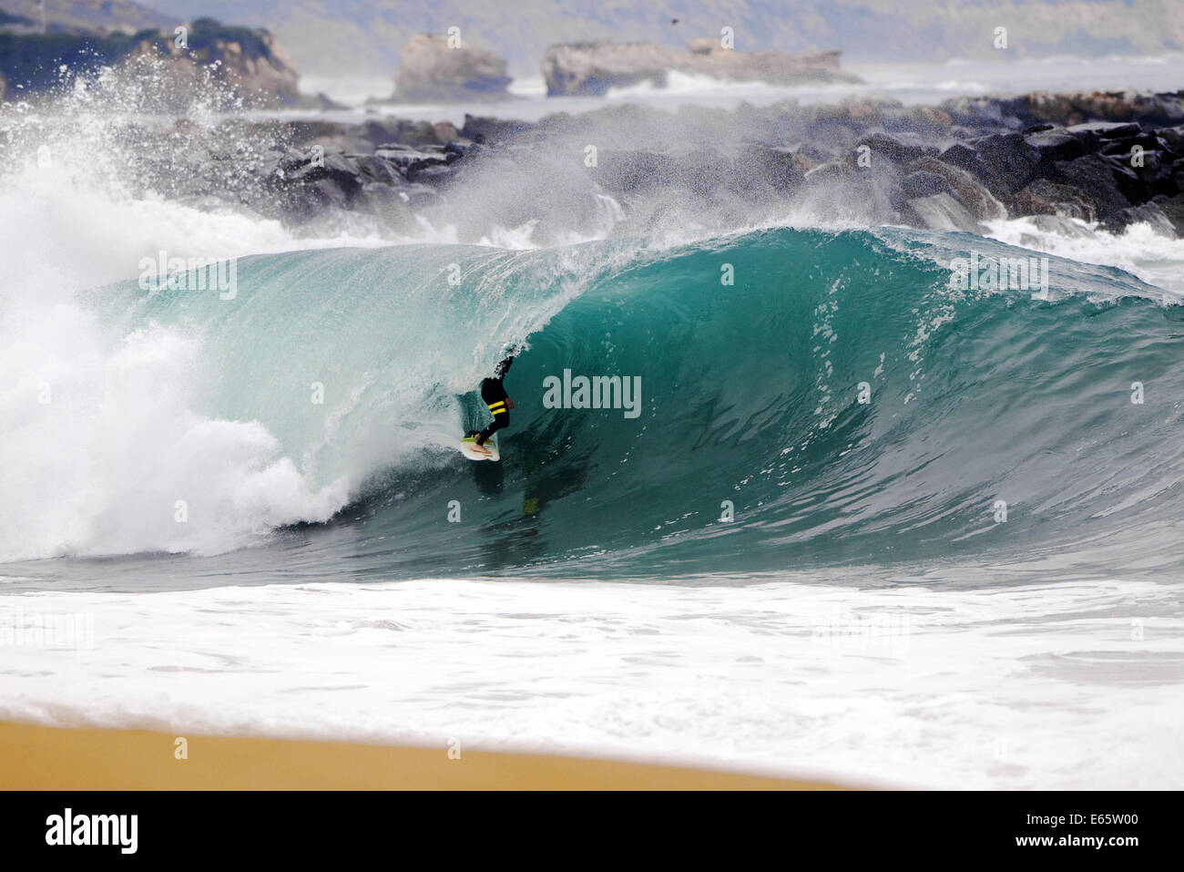 Eine lokale Surfer zieht in eine schwere, Ufer brechen Barrel im seichten Wasser an der Surf Break The Wedge in Newport Beach, Kalifornien Stockfoto