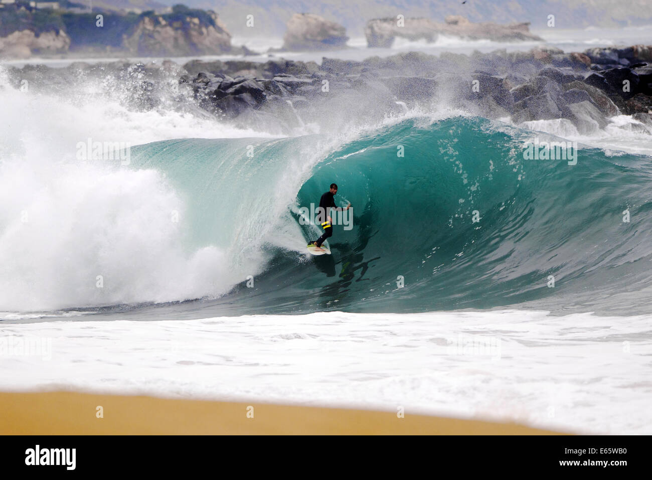 Eine lokale Surfer zieht in eine schwere, Ufer brechen Barrel im seichten Wasser an der Surf Break The Wedge in Newport Beach, Kalifornien Stockfoto