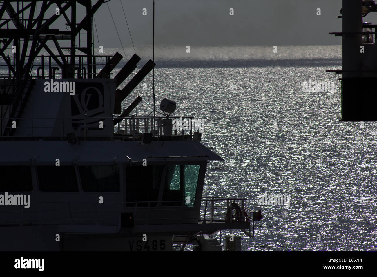 Ein Nordsee liefern Boot neben einer Bohrinsel in der späten Nachmittagssonne Stockfoto
