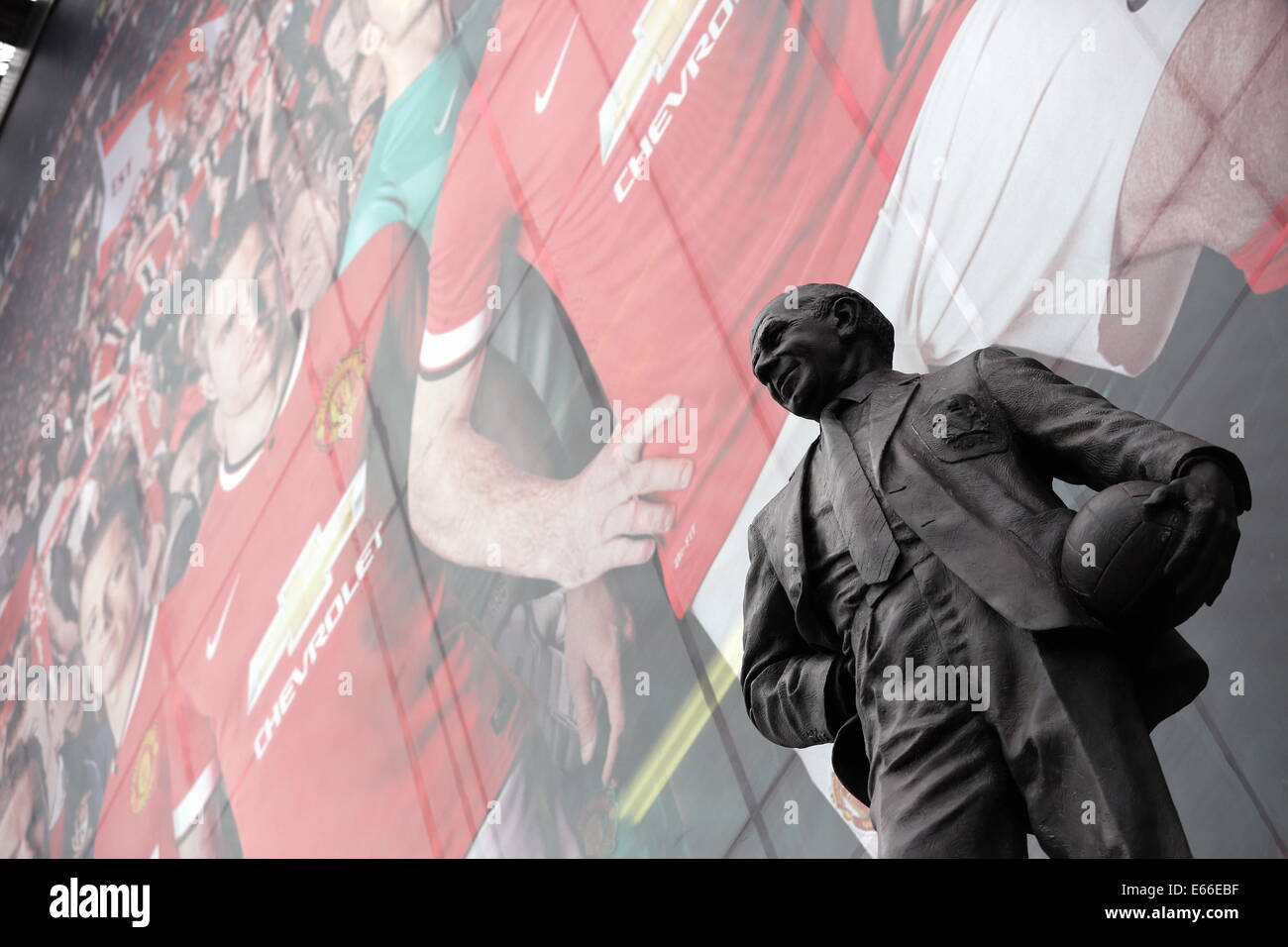 Manchester, UK. 16. August 2014. Im Bild: Die Statue von Sir Matt Busby infront eines Banners mit einer Reihe von Manchester United Spieler außerhalb des Old Trafford. Samstag, 16. August 2014 Re: Premier League Manchester United gegen Swansea City FC im Old Trafford, Manchester, UK. Bildnachweis: D Legakis/Alamy Live-Nachrichten Stockfoto