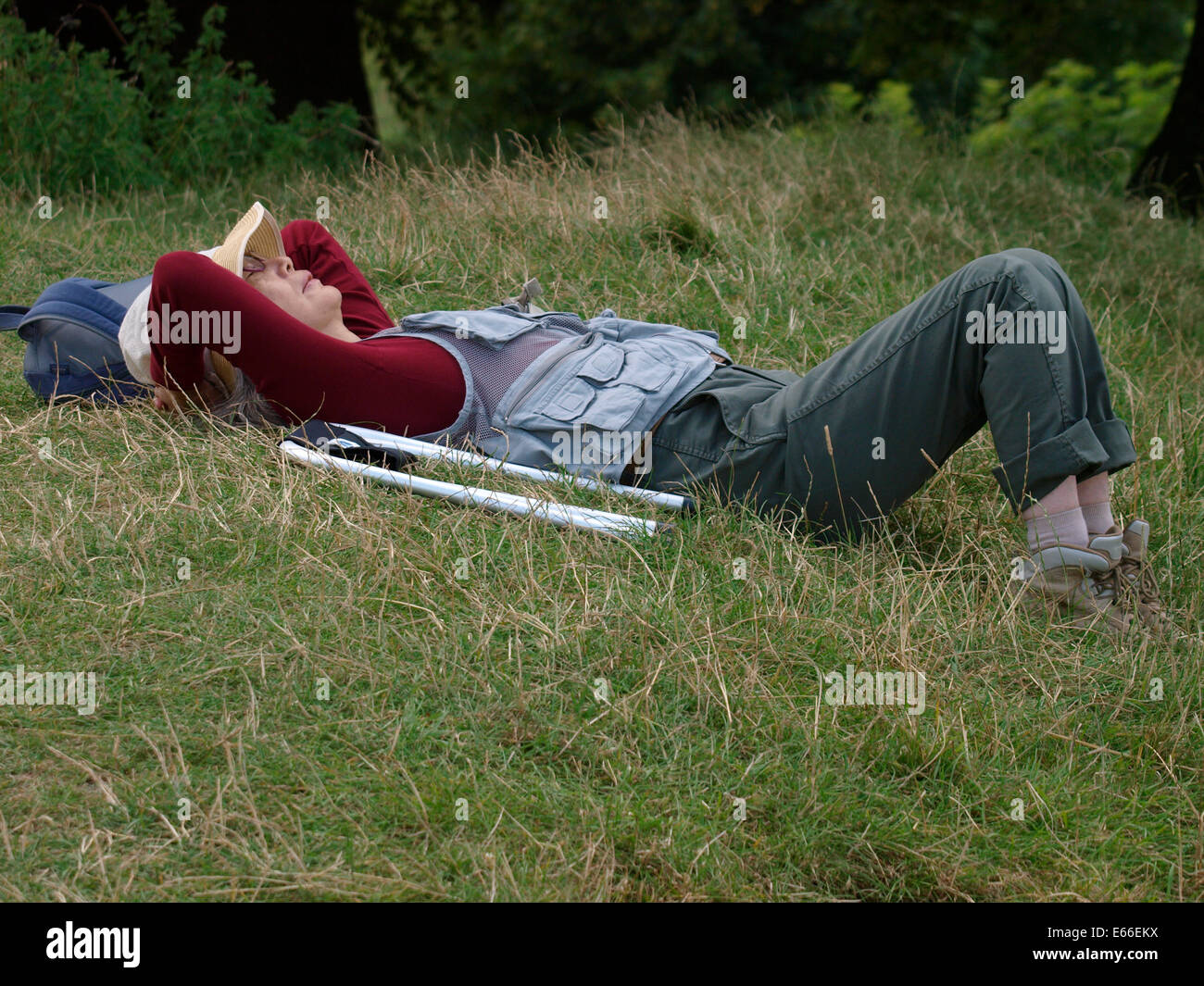 Asiatische Frau, die eine Siesta auf dem Rasen in Avebury, Wiltshire, UK Stockfoto