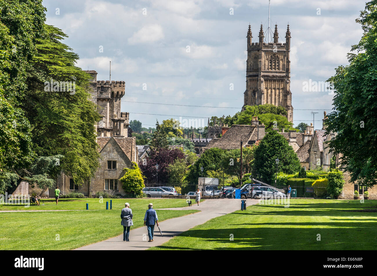 Cirencester Park auf der Bathurst Immobilien. Die laufen in der Sonne. Kirche St. Johannes Baptist hinter sich. Cotswolds, Gloucestershire, England, UK. Stockfoto