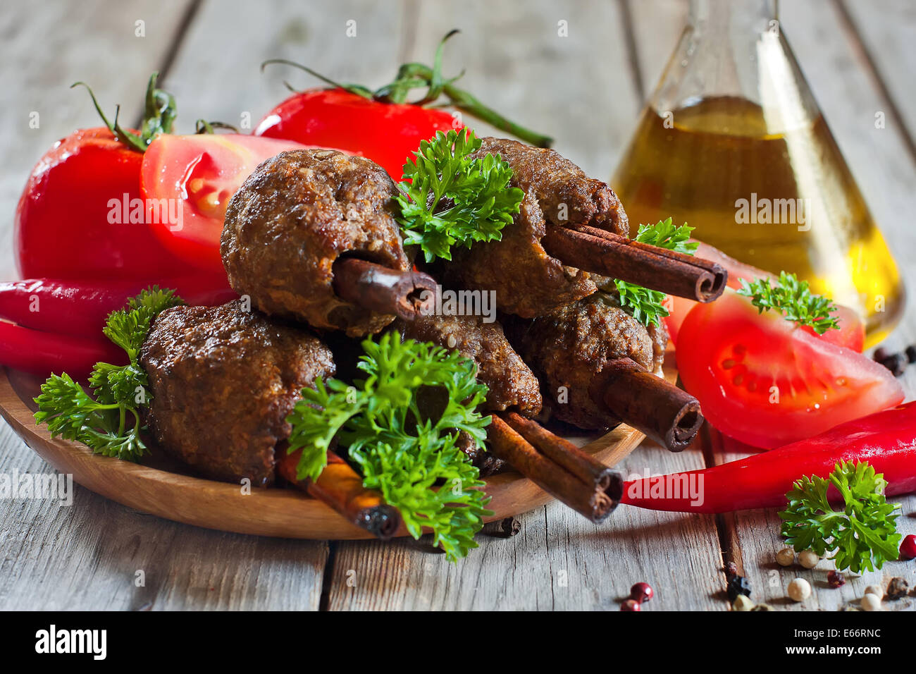 Traditionelles Lamm Kebab auf Zimt-sticks auf Holzplatte mit roten Paprika, Tomaten und Petersilie. Selektiven Fokus. Stockfoto