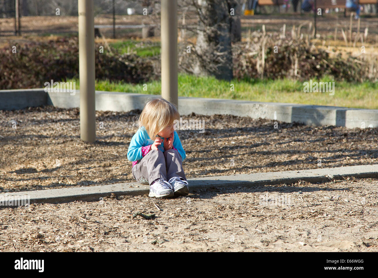 Kaukasische Mädchen sitzen allein in einem Park. Niemand da ist, und sie sieht verloren. Stockfoto