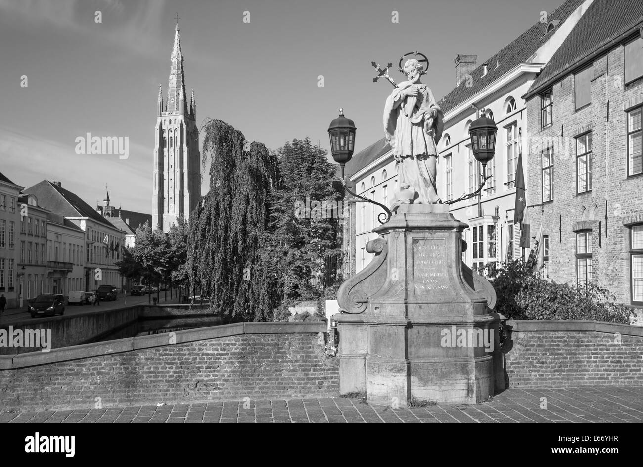 Brügge - der Turm der Liebfrauenkirche und St. Johannes Nepomuk-Statue auf der Brücke. Stockfoto