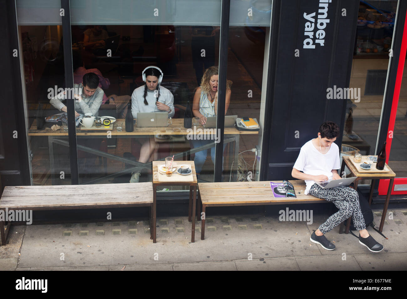 Alte Straße. Holz-Hof-Café gesehen von der Spitze eines Busses mit jungen Menschen, die mit Mac-laptops Stockfoto