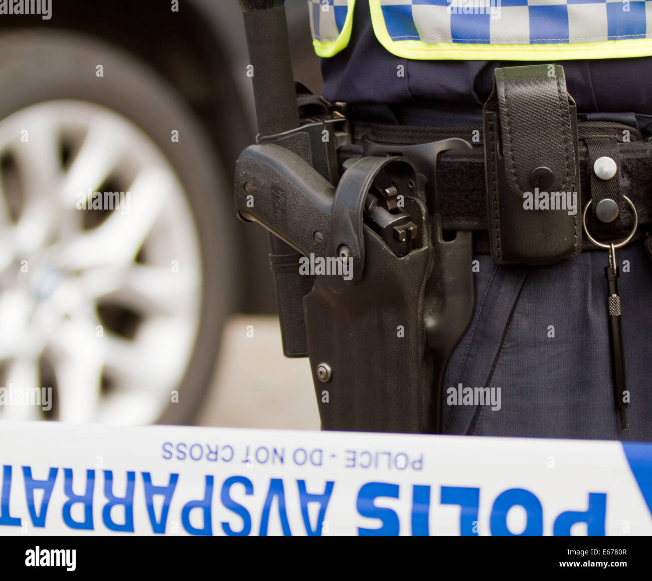 Waffe in einem Pistole Gürtel eines schwedischen Polizisten stehen hinter der Linie, die öffentlichen Eingang abgeriegelt hat. Stockfoto