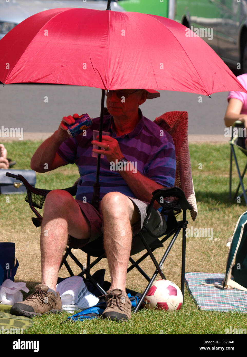 Rentner genießen die Sommersonne saß unter einem Regenschirm, UK Stockfoto