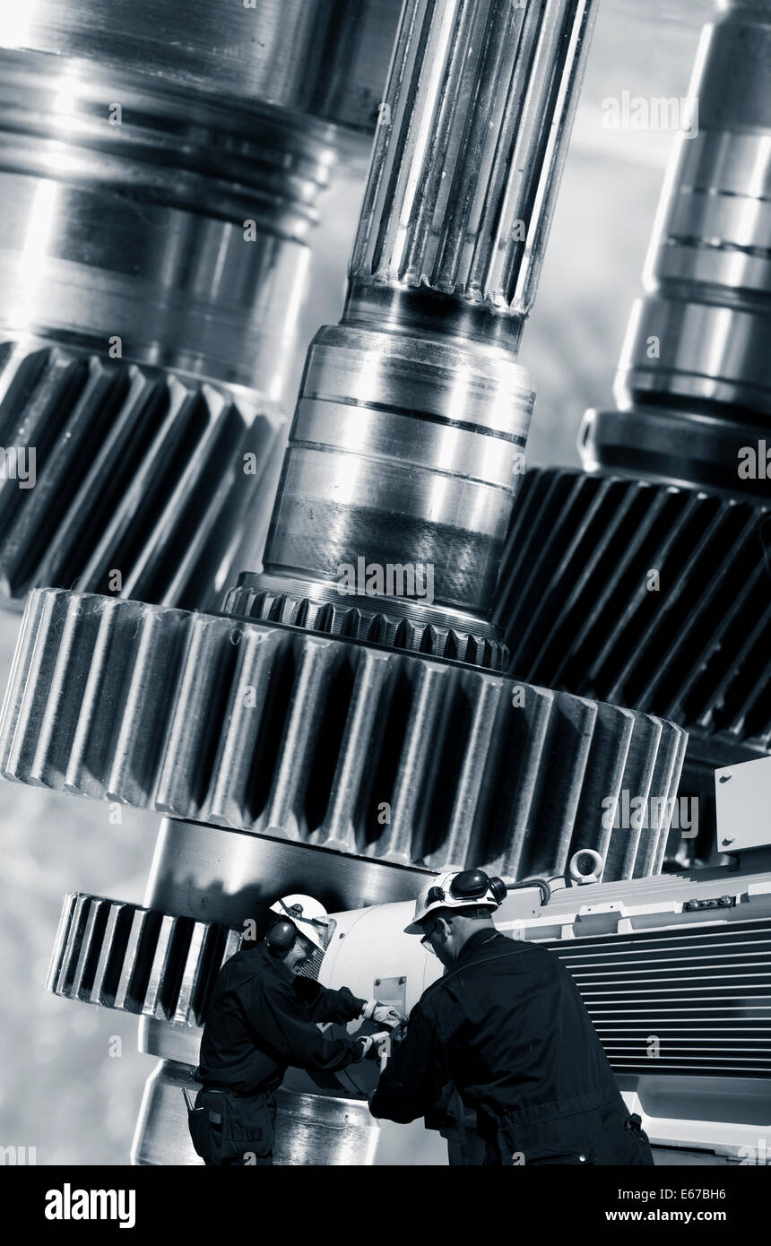 zwei Stahlarbeiter, Ingenieure mit Riesenzahnräder Maschinen im Hintergrund Stockfoto