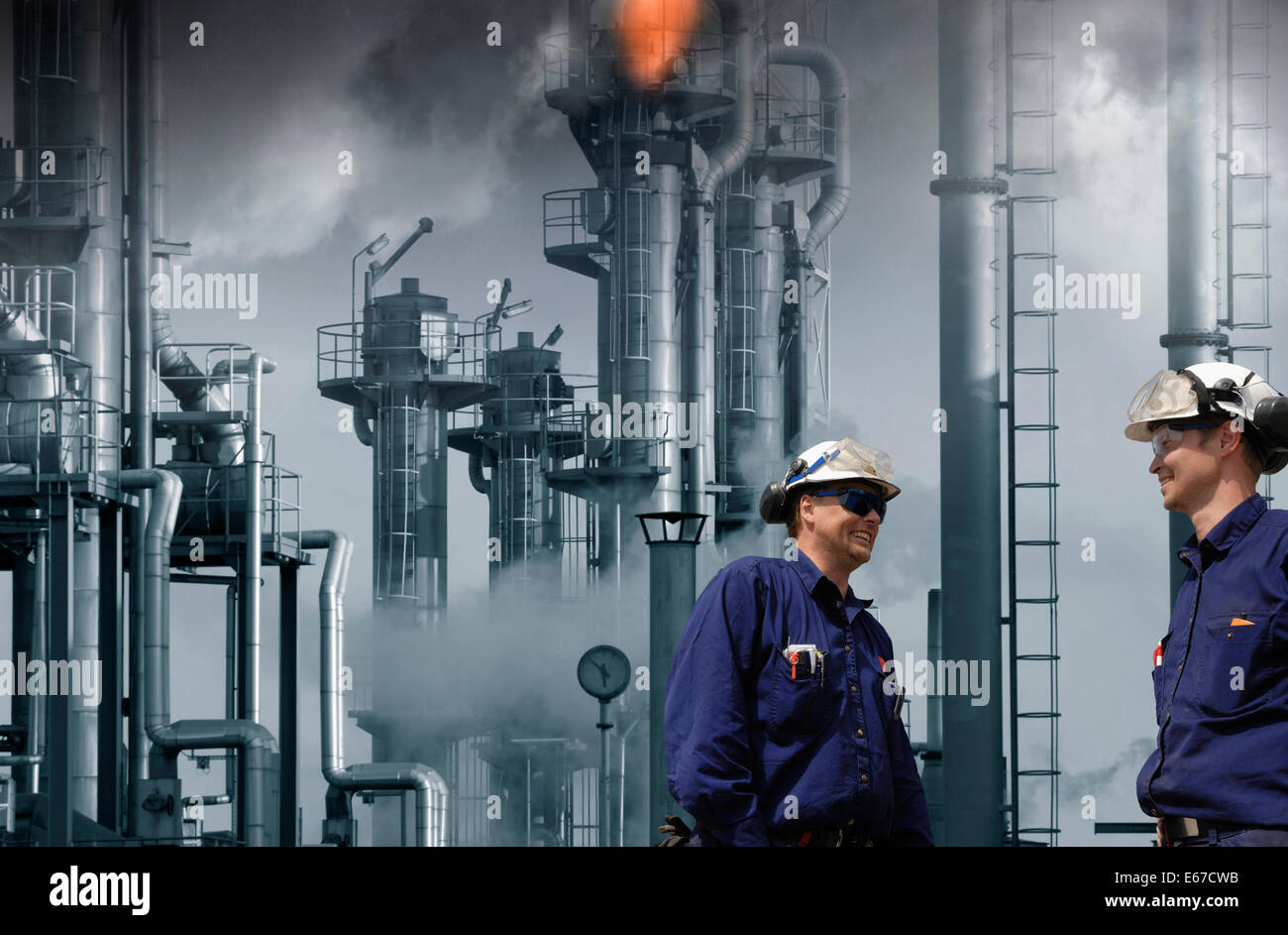 Öl-Raffinerie und Arbeiter, riesige Flammen und Feuer Stockfoto