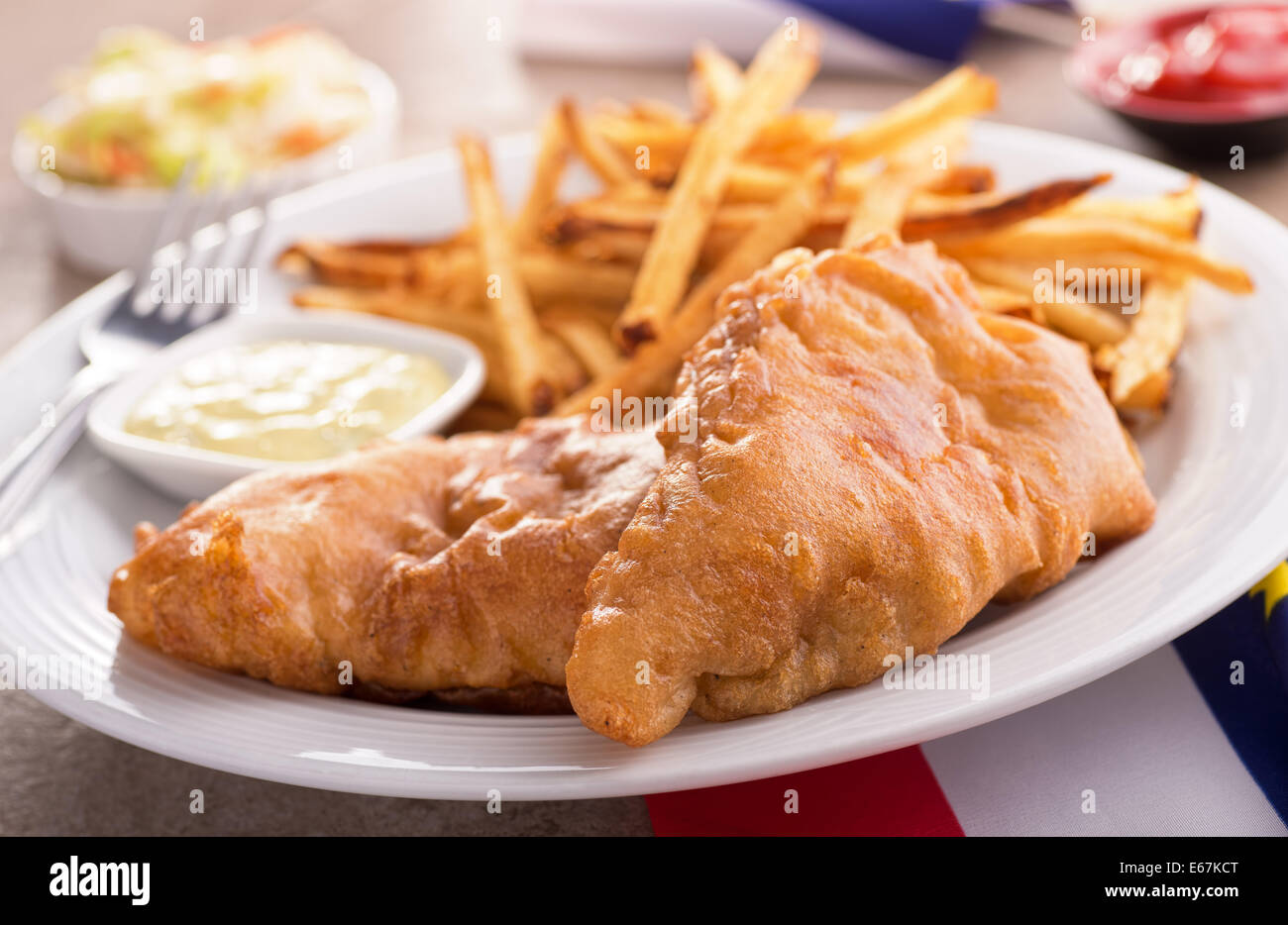 Ein Teller mit leckeren Fish And Chips mit Sauce Tartar und Krautsalat. Stockfoto