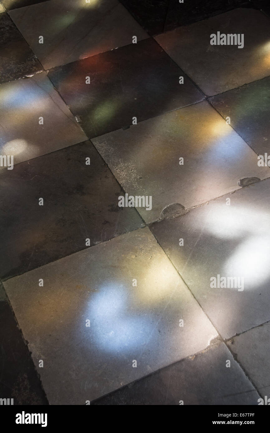 Lichtmuster aus den Glasfenstern auf den Fliesenboden der Kirche wider. Stockfoto