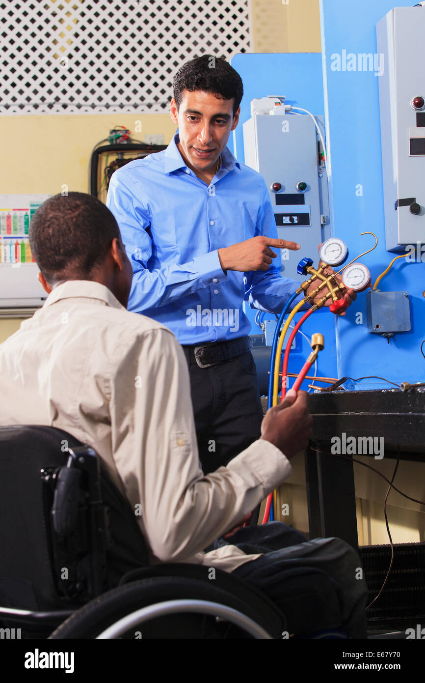 Studierende diskutieren Klimaanlage aufladen Messung System in HVAC Klassenzimmer ein Student im Rollstuhl Stockfoto