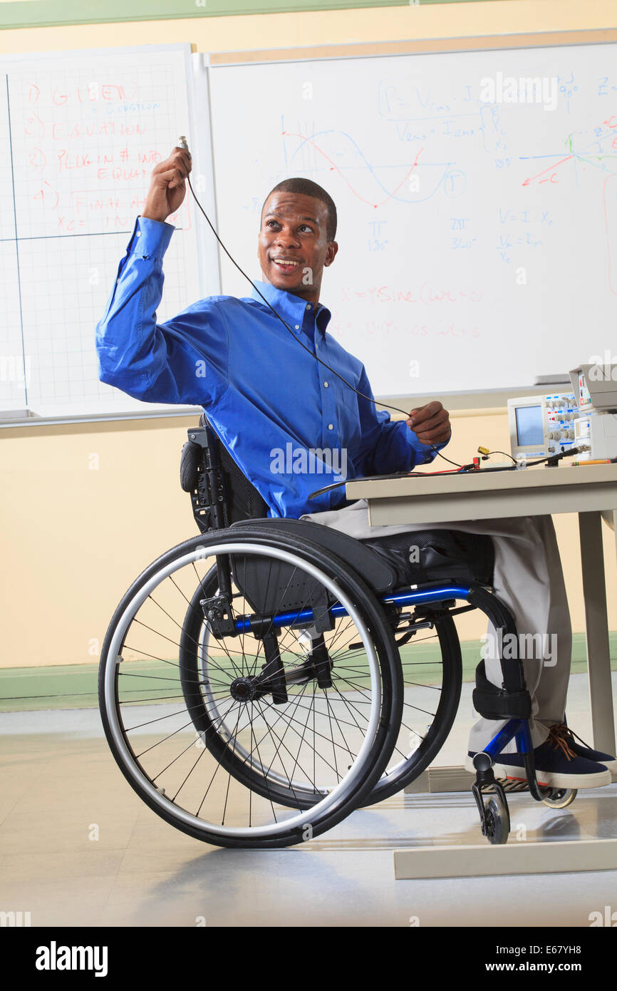 Engineering-Student im Rollstuhl Vorbereitung Laborversuch mit Oszilloskop und elektronische Prototyping Steckbrett Stockfoto