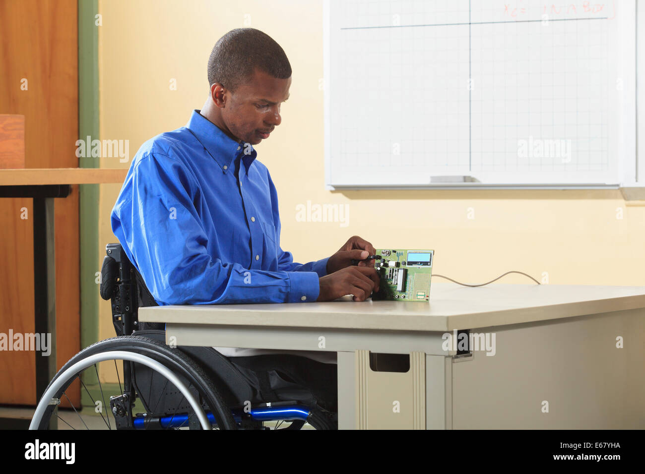 Maschinenbau-Student sitzt in einem Rollstuhl Prüfung Mikroprozessor-Platine für Elektronik-Labor-experiment Stockfoto