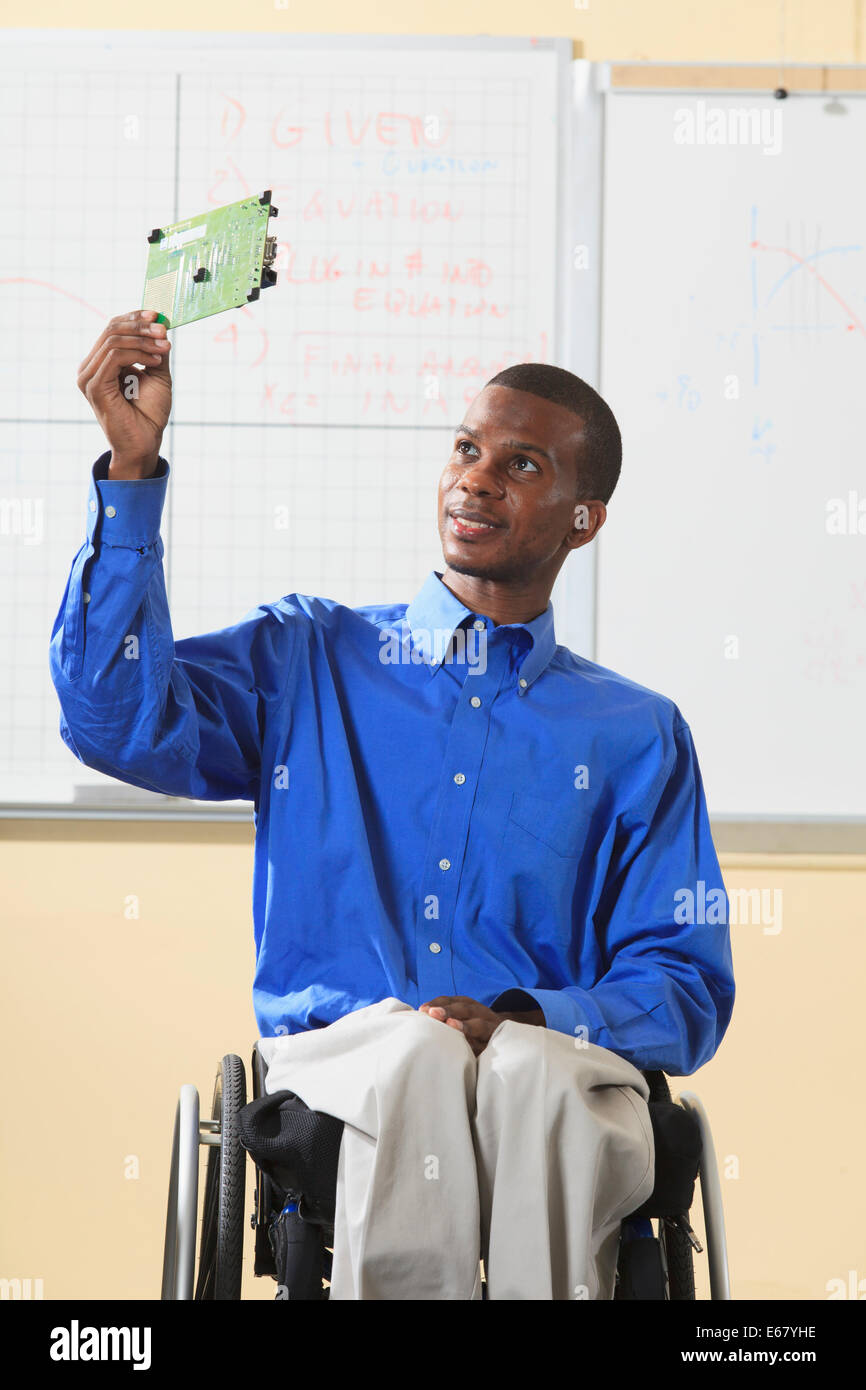 Engineering Student sitzt in einem Rollstuhl vom Rückenmark Meningitis, Mikroprozessor-Platine prüfen Stockfoto