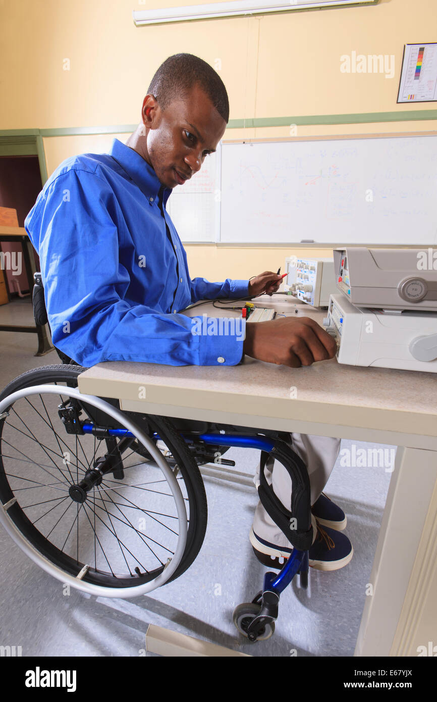 Student der Ingenieurswissenschaften in einem Elektronik-Klassenzimmer in einen Rollstuhl vom Rückenmark Meningitis Vorbereitung ein Prototyping-Steckbrett Stockfoto